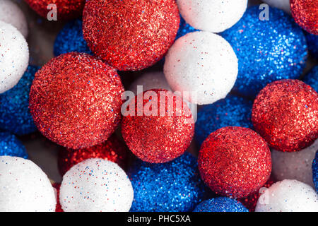 Dimensioni differenti ornamentale bianco rosso e blu glitter di palline in un modello casuale close up piena vista del telaio per Americani patriottici e British temi Foto Stock