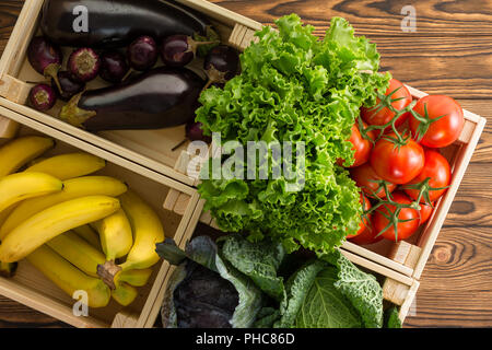 Fresca assortita verdure organiche in scatole di legno sul display in un mercato degli agricoltori visto da vicino dal di sopra su una tavola in legno rustico in una dieta sana c Foto Stock