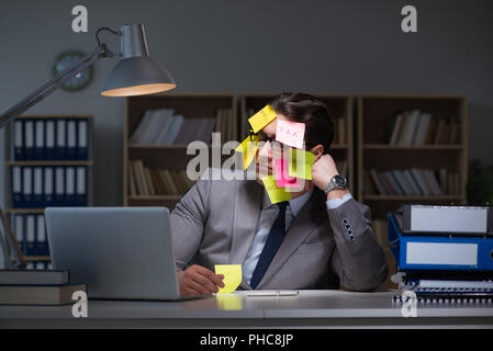 L uomo d affari che soggiornano in ritardo per ordinare le priorità Foto Stock