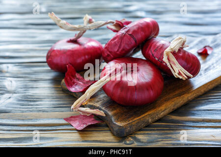 Dolce cipolle rosse su una vecchia tavola di legno. Foto Stock