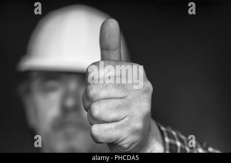 Lavoratore edile che mostra la mano con il pollice in alto Foto Stock