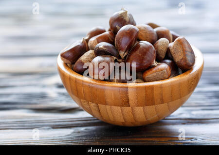 Le castagne fresche in una ciotola di legno. Foto Stock