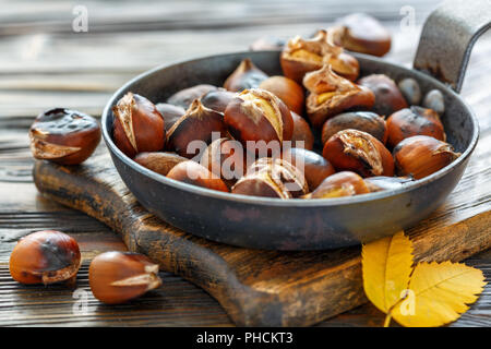 Arrostire le castagne in un tegame closeup. Foto Stock