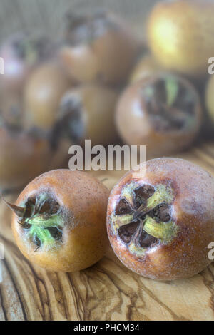 Medlars su una tavola di legno Foto Stock