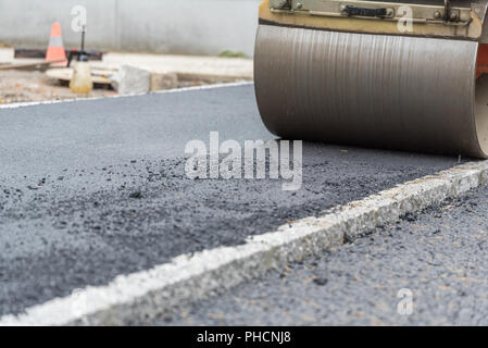 Strada - rullo di compattazione di asfalto al marciapiede Foto Stock