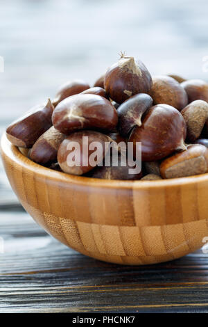 Le castagne fresche in una ciotola di legno. Foto Stock