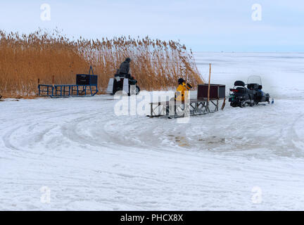 Nida, Lituania, 10 marzo 2018, i pescatori sul ghiaccio pronto per andare in slitta elettrico più lontano dalla riva, motoslitte per la pesca invernale Foto Stock