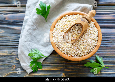 Cucchiaio di legno in una terrina a secco con il farro. Foto Stock