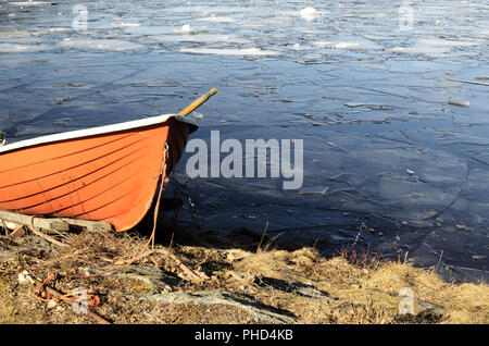 Orange la barca di salvataggio sulla riva di un lago ghiacciato Foto Stock