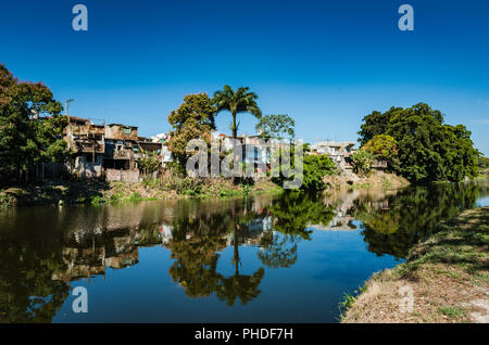 Calma le riflessioni sul fiume Yayabo con vista di abitazioni in Sancti Spiritus , Cuba. Foto Stock