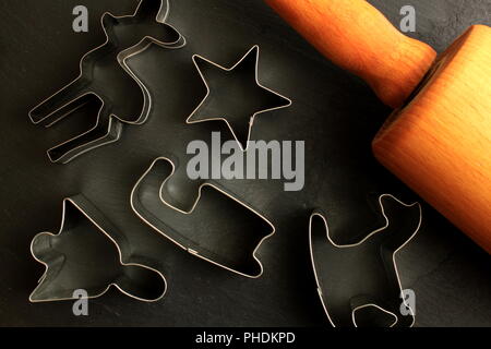 Natale cookie cutter in legno con il mattarello su sfondo nero Foto Stock