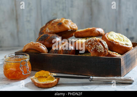 Vassoio di legno con panini e un vasetto di marmellata di arancio. Foto Stock