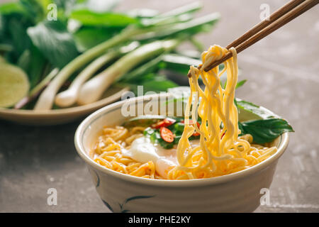 Chiuso fino tagliatelle istante con verdure su chopstick isolate su pietra dảk sfondo, cibo spazzatura o fast food concept. Foto Stock