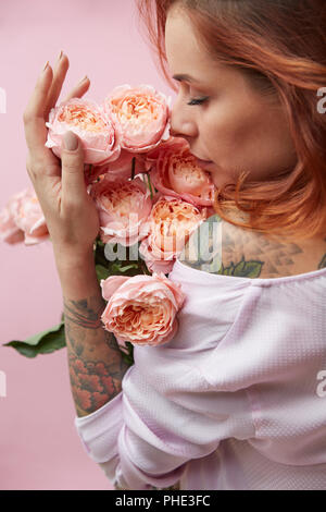 I capelli rossi donna lo sniffing di un profumo di rosa ranuncukus Foto Stock