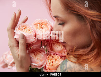 Carino donna lo sniffing è un profumo di rosa Buttercup Asian Foto Stock