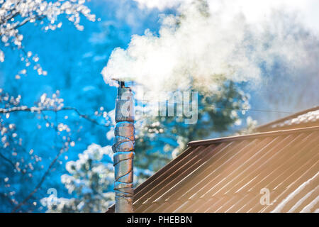 Il fumo dal camino sul tetto Foto Stock