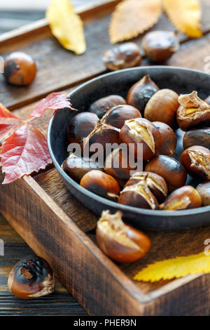 Castagne arrostite in una padella in ghisa. Foto Stock