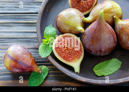 Fichi freschi e foglie di menta su un tagliere di legno. Foto Stock