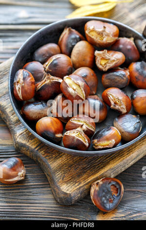 Arrostire le castagne in un tegame closeup. Foto Stock