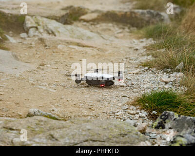 RC moderno fuco / Quadcopter con fotocamera battenti in montagna Vysoke Tatry in Slovacchia. Piccolo dron atterraggio sul sentiero. Foto Stock