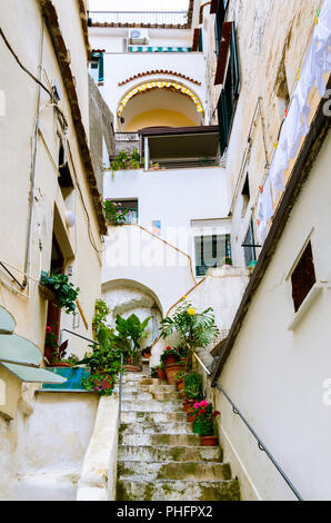 Strada stretta e un cortile nella città di Amalfi, Italia meridionale - scale portano alle porte di edifici residenziali Foto Stock