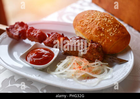 Kebab spiedini giacente su una piastra con salsa Foto Stock