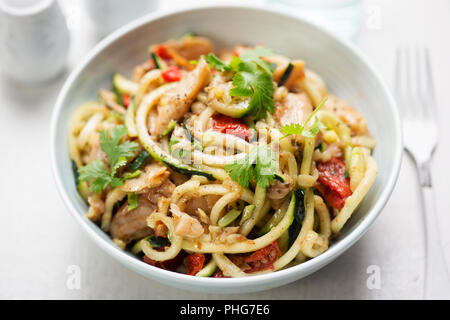 Vegetariano stir fry con peperoncino e coriandolo bocconcini di soia con spiralata spaghetti di zucchine e semi pomodori secchi Foto Stock