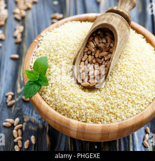 Convogliatore con il grano in una ciotola di legno con cuscus. Foto Stock