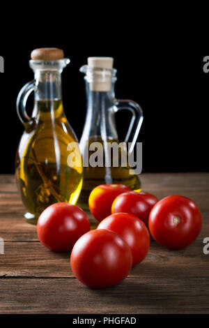 Pomodori e bottiglie di olio d'oliva sul tavolo rustico Foto Stock