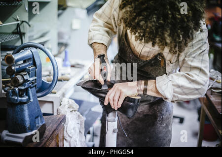 Calzolaio regola la suola di scarpa nel suo laboratorio Foto Stock