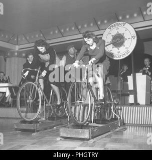 1950s donne in bicicletta. Due giovani donne partecipano a una competizione su chi sta raggiungendo la velocità più alta quando si guidano le moto su una macchina che la misura. È la società norvegese Gresvig che è l'organizzatore dell'evento. L'azienda era il più grande produttore di sci e biciclette di Norways, e il loro modello di bicicletta superiore era il diamante. Svezia 1950. Foto Kristoffersson AX21-8 Foto Stock