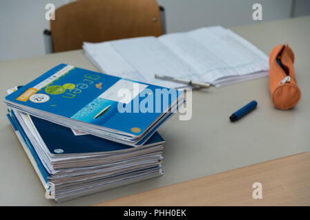 Pila di compiti scolastici presso l'insegnante di scrivania mentre la correzione Foto Stock