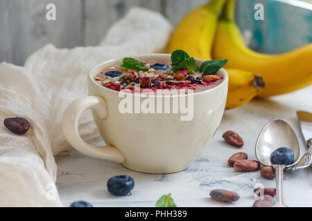 Ciotola frullato al cioccolato, le fave di cacao e mirtilli. Foto Stock