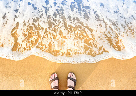 Donna in piedi sandali su una spiaggia di sabbia Foto Stock