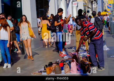 Una strada hawker 'Top Manta' vendita falsi borsette in Gran Via piena di gente. Foto Stock