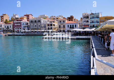 Agios Nicolaos, Creta / Grecia. Turisti e persone locali sono rilassanti presso il caffè accanto al mare di Agios Nikolaos cittadina Foto Stock