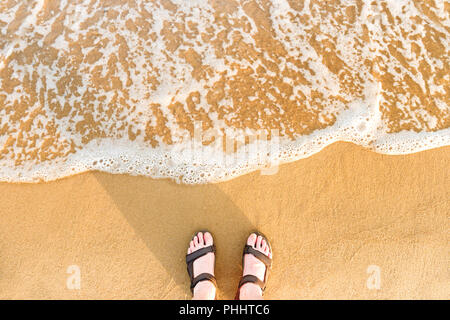 Donna in piedi sandali su una spiaggia di sabbia Foto Stock