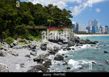 Haeundae Bay, Busan, Corea. Costa frastagliata con piccola baia e percorso pedonale e ponte in Dongbaek Park Foto Stock