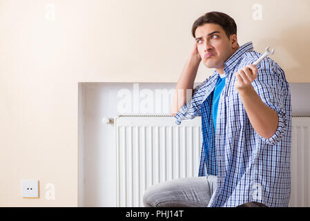 Giovani repairman contraente la riparazione del pannello di riscaldamento Foto Stock