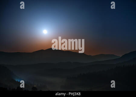 Luna crescente al di sopra delle montagne di notte Foto Stock