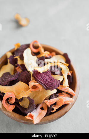 Vari chip vegetali su sfondo grigio, copia dello spazio. Assortiti bietola disidratata, carota, zucca chip di vegetali - vegano sani snack. Foto Stock