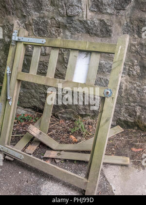 Rotto / fracassato garden gate sostennero contro il muro di pietra. Foto Stock