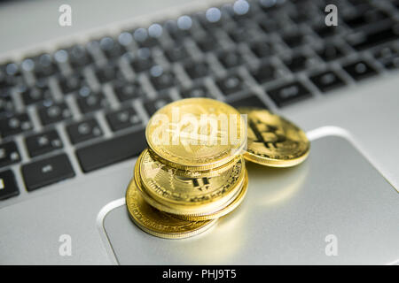 Una pila di golden bitcoin moneta su un argento tastiera del laptop. Virtual cryptocurrency concetto. Estrazione di bitcoins bussiness online. Bitcoins trading Foto Stock