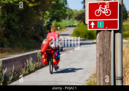 Cartello stradale su un percorso ciclabile numero uno con un ciclista viaggia in background, Norvegia meridionale Foto Stock