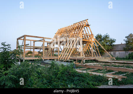 Telaio in legno edificio residenziale in costruzione. Nuove costruzioni residenziali home framing contro un cielo blu al tramonto. Foto Stock