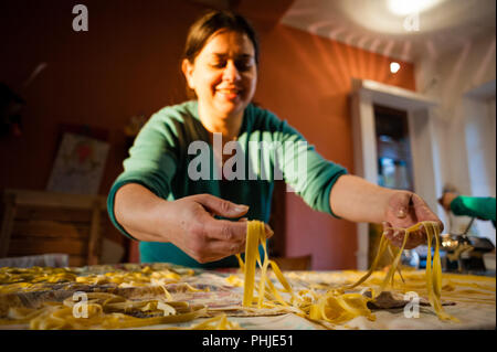 40 anno vecchia donna si prepara la pasta fresca all'uovo tagliatelle fatte in casa Foto Stock