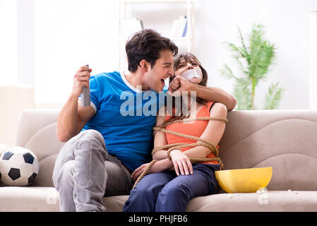 L'uomo la legatura fino a sua moglie di guardare lo sport calcio Foto Stock
