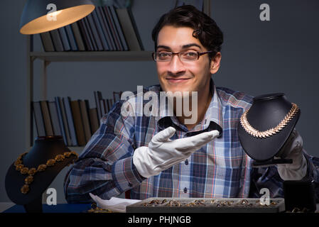 Giovane maschio gioielliere lavorando di notte nel suo laboratorio Foto Stock