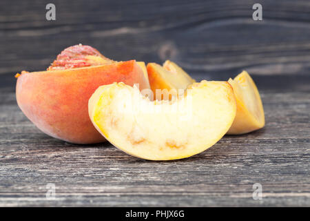 Tagliare pesca matura con tracce all'interno di rot e degrado, close-up di frutta sul bordo di taglio Foto Stock