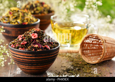 Composizione con tazza di tè e ciotole di foglie di tè. Foto Stock